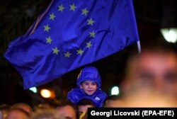 A young boy smiles under the EU flag during a rally in support of the upcoming referendum to endorse a name change for Macedonia.