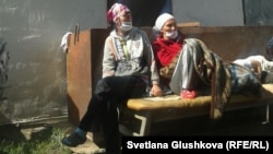 Две участницы голодовки сидят перед забаррикадированным входом в дом Алтын Червалиевой, который попадает под снос. Астана, 8 августа 2014 года. 