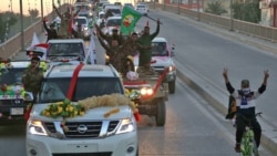 Members of the Hashed Shaabi (Popular Mobilisation) paramilitary forces flash the victory gesture as they wave flags of the organisation and its groups while parading in the streets of the central holy shrine city of Karbala on December 10, 2018