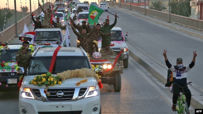 Members of the Hashed Shaabi (Popular Mobilisation) paramilitary forces flash the victory gesture as they wave flags of the organisation and its groups while parading in the streets of the central holy shrine city of Karbala on December 10, 2018