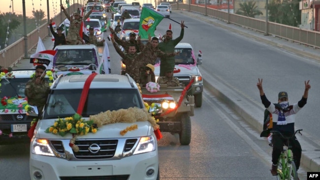 Members of the Hashed Shaabi (Popular Mobilisation) paramilitary forces flash the victory gesture as they wave flags of the organisation and its groups while parading in the streets of the central holy shrine city of Karbala on December 10, 2018