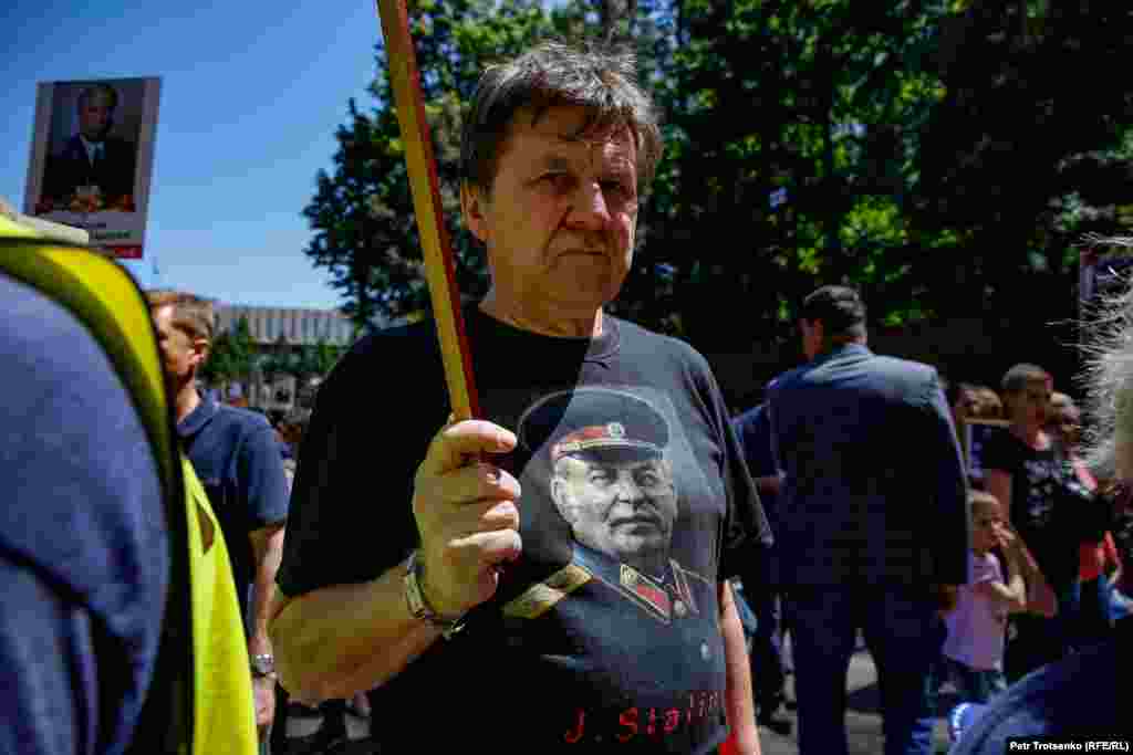 Мужчина в футболке с портретом Иосифа Сталина. Изображения со Сталиным, красные флаги и советская военная форма времен Великой Отечественной войны – самые распространенные атрибуты праздника. Алматы, 9 мая 2019 года.