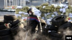 A protester guards the barricades during antigovernment protests in Kyiv on January 27.