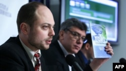 Владимир Кара-Мурза (слева) держит копию отчета о коррупции на Олимпийских играх в Сочи в 2014 году во время пресс-конференции в Национальном пресс-клубе в Вашингтоне, округ Колумбия.