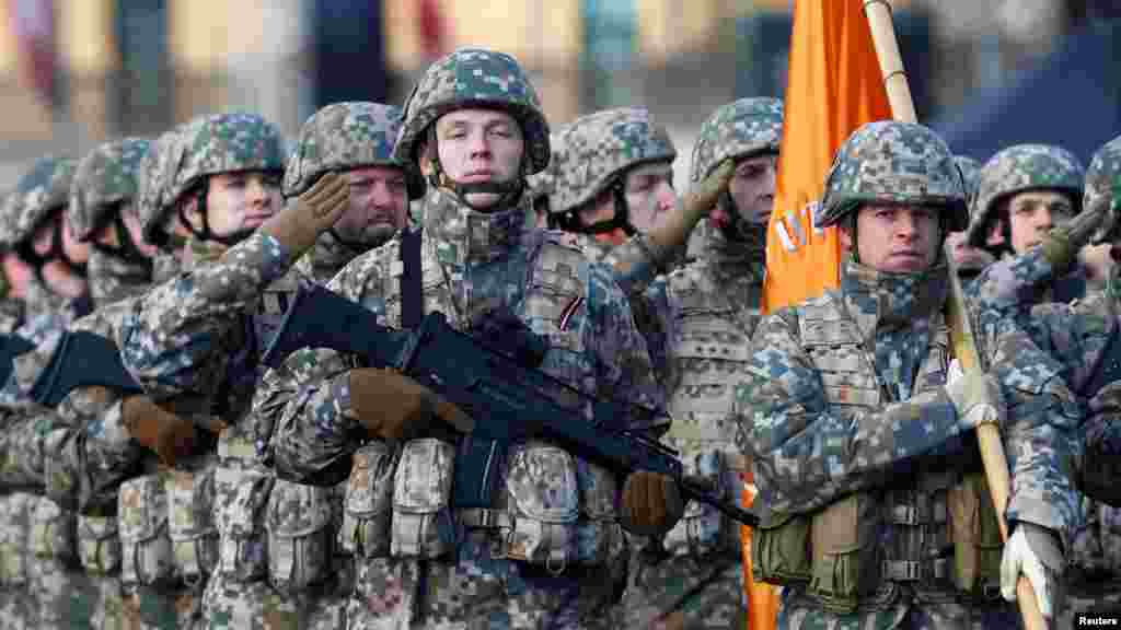 Озброєні латвійські солдати на параді віддають честь