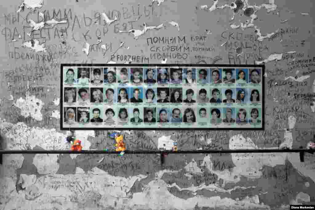 At School No. 1, portraits of more than 300 victims hang in the gymnasium where 1,100 children, parents, and teachers were held hostage for 52 hours. The school stands in ruins, and the room itself has been largely untouched since 2004. Bullet holes and haunting inscriptions of &quot;we remember&quot; adorn the walls; there is a charred gym ladder to one side and blackened basketball hoops at either end. An Orthodox cross has been placed in the middle of the gym floor, surrounded by freshly opened bottles of water left to commemorate the captives, who endured over two days in fierce summer heat with almost no water. Residents continue to bring teddy bears, model cars, and other toys in memory of the 186 children who were killed here. &nbsp;
