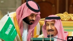 Saudi Crown Prince Mohammed bin Salman, left, speaks to his father, King Salman, right, at a meeting of the Gulf Cooperation Council in Riyadh, Saudi Arabia, Sunday, Dec. 9, 2018. 