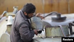 Syria - A worker inspects the final fuel product at a makeshift oil refinery site in Marchmarin town, southern countryside of Idlib, Syria December 16, 2015