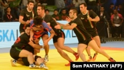 Korea's player tries to break a cordon by Iran's players during the semi-final match between Iran and Korea of the 2016 Kabaddi World Cup at the Transstadia in Ahmedabad on October 21, 2016.