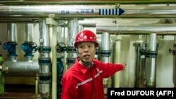Работник в компанията "Синопек" показва на журналисти как финкционира топлинна помпа. Китай, февруари 2017 г. 