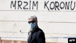 Čovjek sa zaštitnom maskom prolazi pored grafita na kom piše "mrzim koronu" u Zagrebu, 17. april 2020.