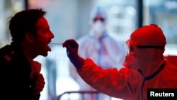 Медицинский работник берет у пациента тест на коронавирус в специальном пункте, где обслуживаются «люди опасных профессий» – полицейские, медсестры, пожарные. Германия, Кельн