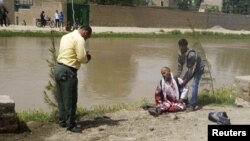 A wounded man sits near the scene of a suicide attack near a government compound in Baghlan Province on May 20 that killed at least 14 people.