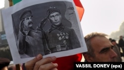 A man holds a poster depicting Vladimir Putin saluting alongside Josef Stalin during a protest in Bulgaria in 2008.