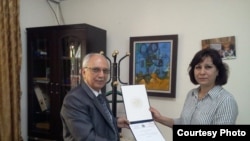 RFI correspondent Faiqa Rasul Srhan receives her certificate of merit from the cultural attaché for the Iraqi Embassy in Jordan.