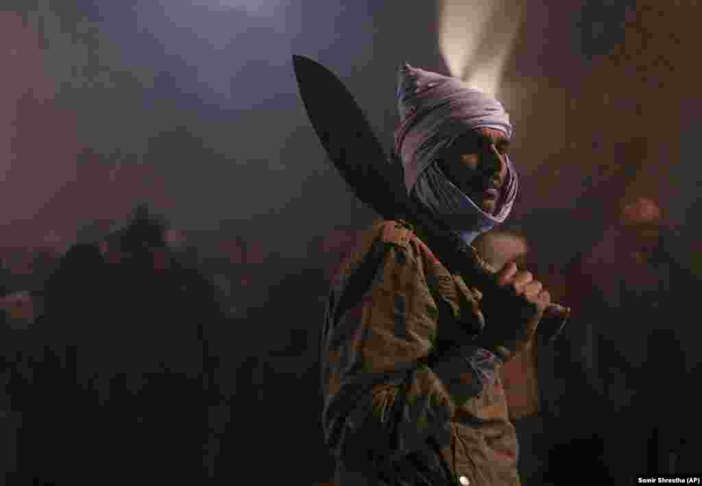 A butcher gets ready to sacrifice animals during the Gadhimai festival in Bariyarpur, south of Kathmandu, Nepal. Hundreds of thousands of Hindus gathered at a temple there for a ceremony involving the slaughter of thousands of animals. (AP/Samir Shrestha)