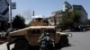 An Afghan policeman covers himself as smoke rises from the site of an attack in Kabul on July 31.