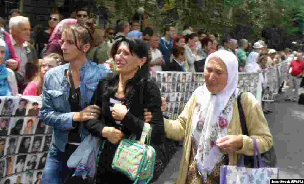 Bosnian women cry while watching a truck, one of three carrying 409 coffins of newly identified victims.