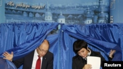 Arseny Yatsenyuk (left), heads a union of opposition parties, and his wife Theresa leave voting booths at a polling station during the parliamentary elections in Kiev.