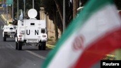 خودروهای مأموریت یونیفل در جنوب لبنان که از مقابل پرچم جمهوری اسلامی عبور می‌کنند. این منطقه در کنترل حزب‌الله است که از سوی تهران پشتیبانی می‌شود