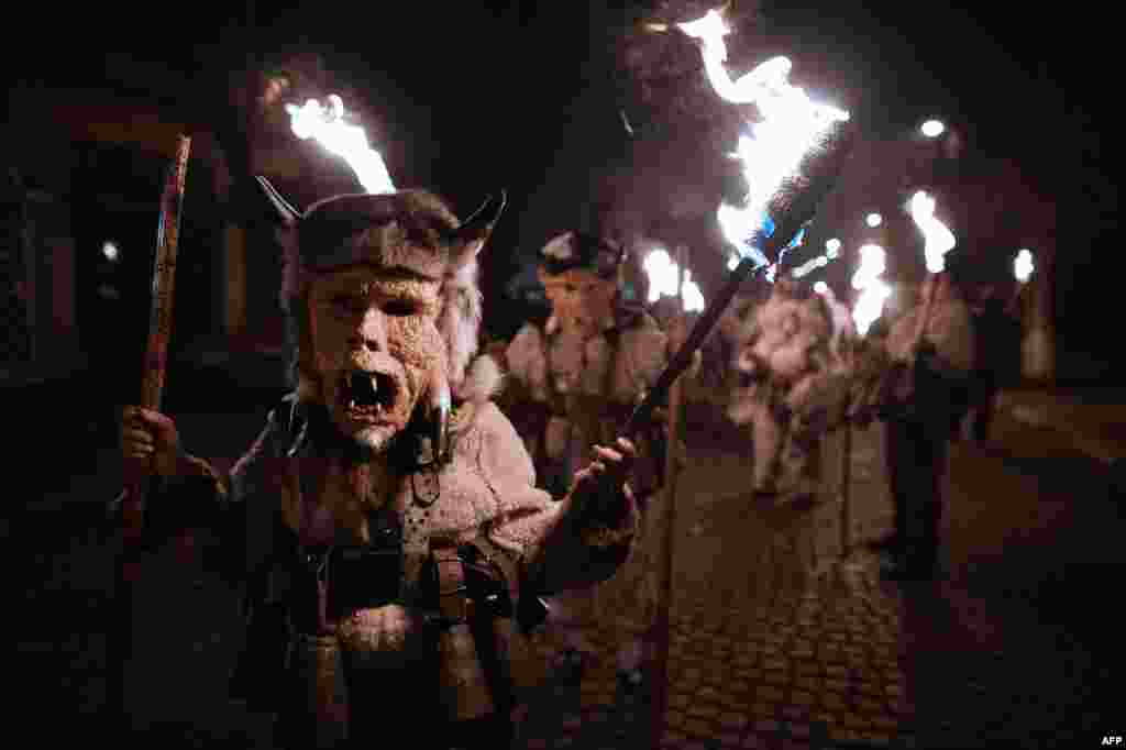 Costumed Bulgarian revelers named &quot;Kukeri&quot; hold torches as they take part in the Kukeri Carnival in the village of Batanovci on January 13. (AFP/Dimitar Dilkoff)