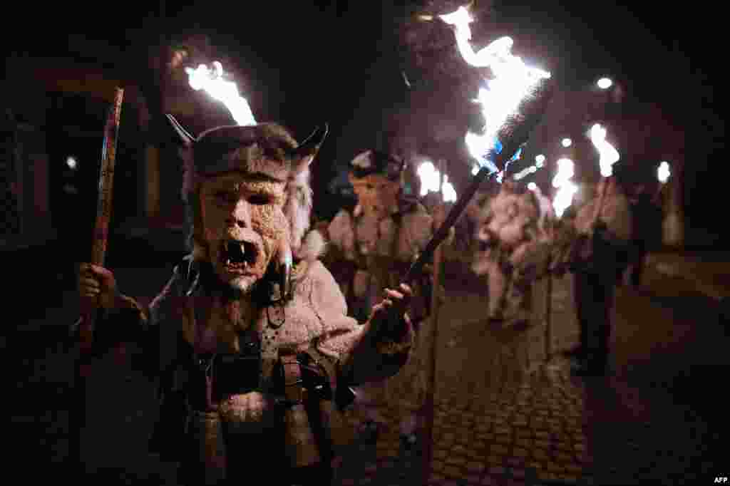 Costumed Bulgarian revelers named "Kukeri" hold torches as they take part in the Kukeri Carnival in the village of Batanovci on January 13. (AFP/Dimitar Dilkoff)