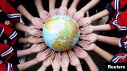 China -- Students pose for a photo with a globe during a campaign to mark World Earth Day in a middle school in Dexing, Jiangxi province, 19Apr2011