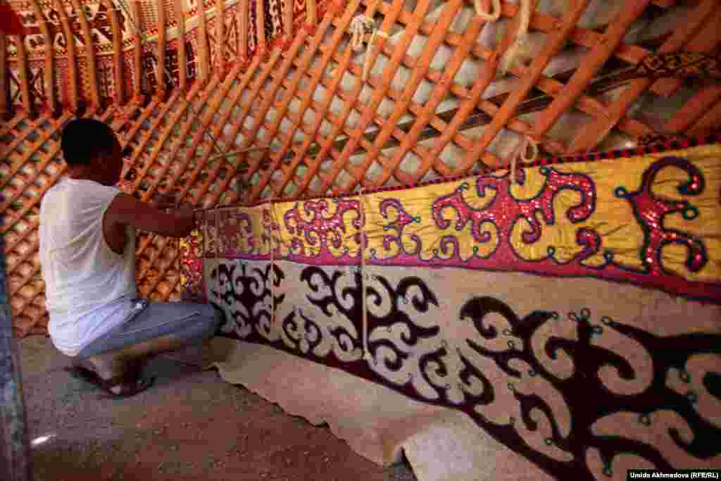 Astara&#39;s eldest son, Dulat, one of nine children, helps to decorate the inside of the yurt.