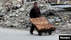 A man selling pastries walks past the rubble of damaged buildings in the rebel held al-Shaar neighborhood of Aleppo on February 10.