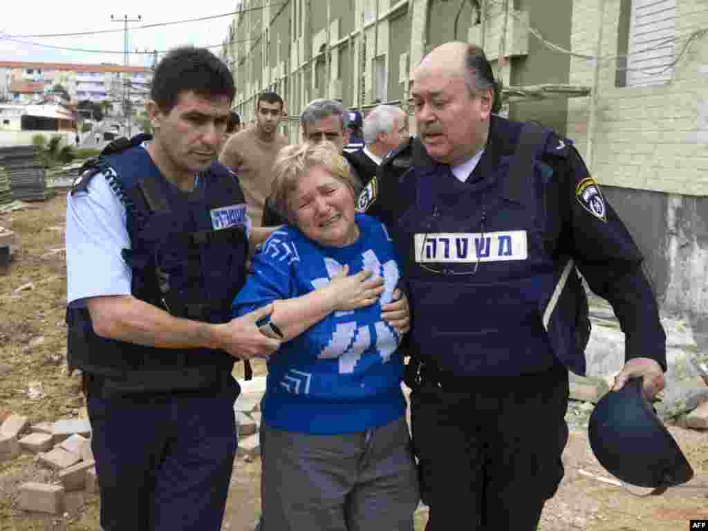 ISRAEL, Sderot : Israeli policemen help an Israeli woman in shock following a rocket attack from Gaza on the southern Israeli town of Sderot December 29, 2008. Israel bombed Gaza for a third day in an "all-out war" on Hamas, as tanks massed on the border and the Islamists fired deadly rockets to retaliate for the blitz that has killed nearly 320. Sderot, located next to the Palestinian territory, is regularly targeted by Gaza militants.