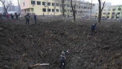 Soldați ucraineni inspectează un crater după atacul aerian asupra maternității din Mariupol, Ucraina, miercuri, 9 martie 2022.