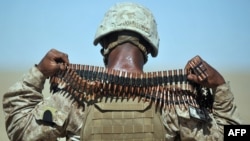 A U.S. Marine removes a bandolier of ammunition from around his neck during a group shooting lesson for Afghan police in Helmand Province.