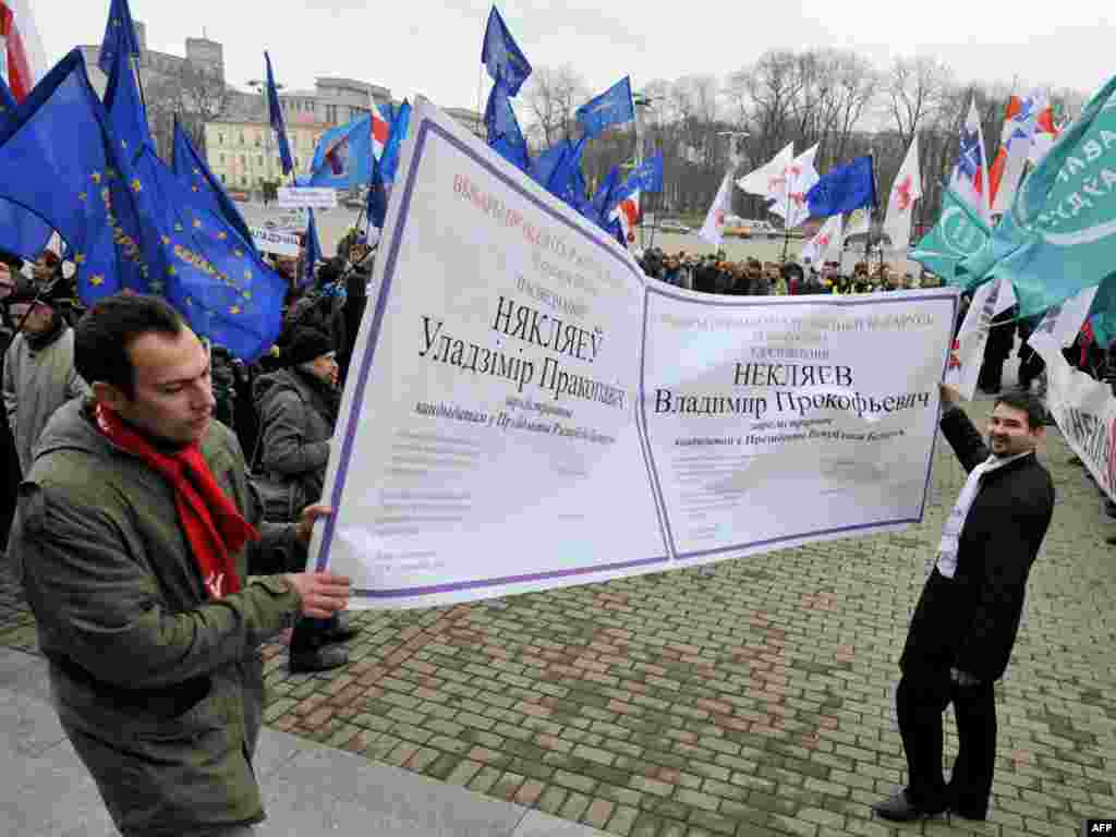 Two supporters of Belarusian presidential candidate Uladzimer Nyaklyaeu hold a replica of his certificate after he was registered as a candidate for the presidential elections in Minsk on November 18. Ten candidates were registered to run in the upcoming vote, authorities said, even though observers say a victory for the incumbent president is a foregone conclusion. The election is scheduled for December 19. Photo by Viktor Drachev for AFP