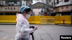 Një grua shihet me maskë mbrojtëse kundër pandemisë, rrugëve të Kinës. Fotografi nga arkivi.