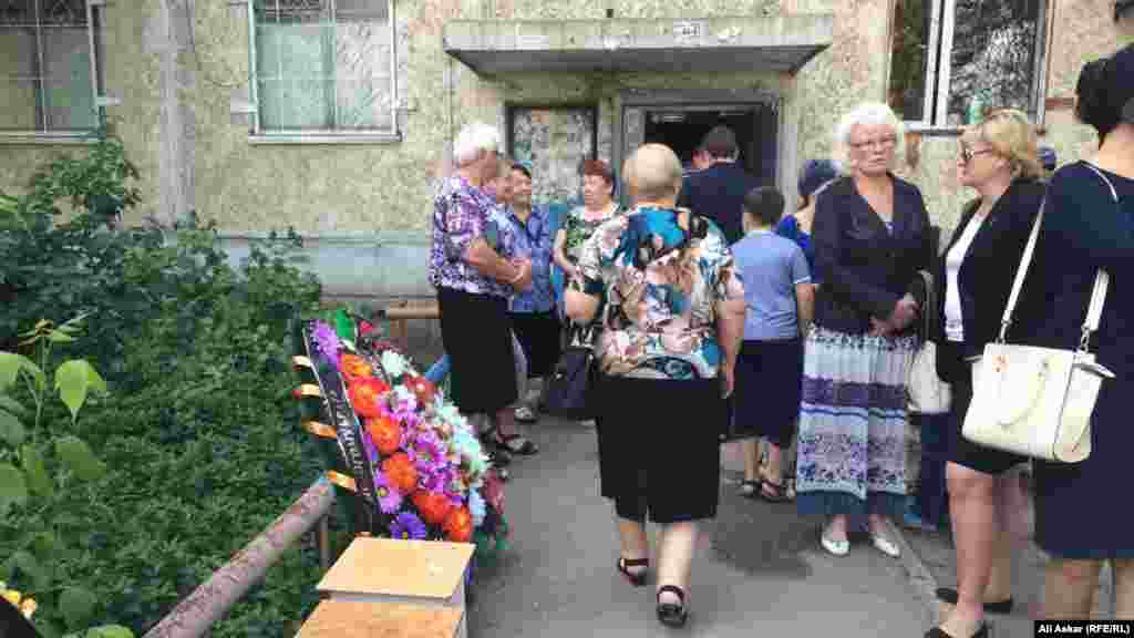 Прощание с еще одним погибшим в ходе теракта, 68-летним Николаем Онищенко, началось в 10 часов утра возле дома №12 по улице Алии Молдагуловой. Магазин &laquo;Паллада&raquo; находится на первом этаже здания.