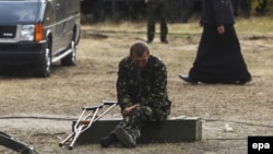 Раненый солдат сидит у медпункта недалеко от города Сватово в Луганской области в Украине. 30 сентября 2014 года.