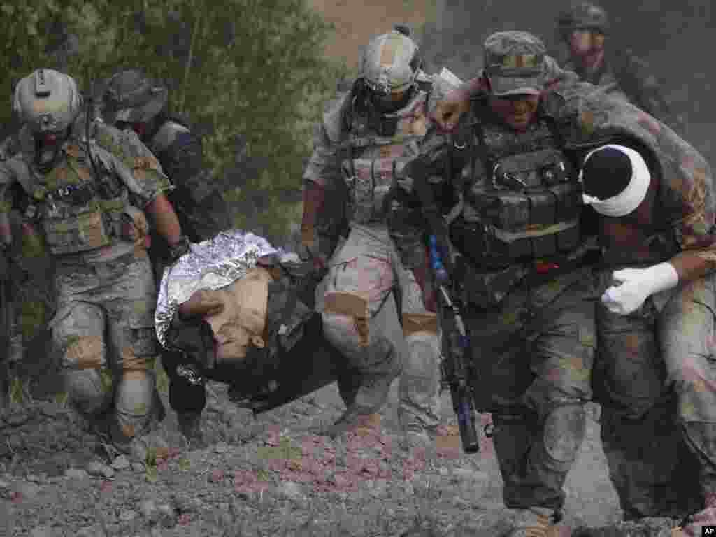 An Afghan National Army soldier carries a wounded colleague as U.S. troops carry another wounded Afghan soldier to a medical-evacuation helicopter following a roadside bomb attack on the outskirts of Kandahar, Afghanistan, on July 29. Photo by Rafiq Maqbool for AP