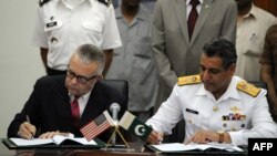 Deputy U.S. Ambassador in Islamabad Richard Hoagland (left) and the head of Pakistani delegation, Rear Admiral Farrukh Ahmed, sign the supply agreement in the Pakistani Defense Ministry in Rawalpindi on July 31.