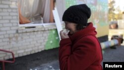A woman cries outside a local kindergarten that was damaged by the explosions at the military depot in Svatove.