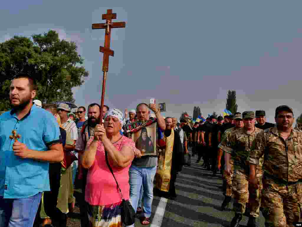 Ukrainian police escort believers and priests of the Ukrainian Orthodox Church of the Moscow Patriarchate -- an affiliate of the Russian Orthodox Church -- during a procession near the town of Boryspil in the Kyiv region on July 25. (epa/Roman Pilipey)