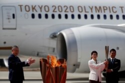 Триразові олімпійські чемпіони Тадахіро Номура і Саорі Йосіда разом з головою оргкомітету Токійської Олімпіади Йосіро Морі зустрічають олімпійський вогонь на військовій авіабазі Сил самооборони Японії