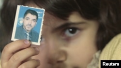 A family member of Dirar Abu Sisi holds his picture at his home in Gaza City.