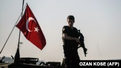 یک نیروی پلیس ضد شورش در کنار پرچم ترکیه