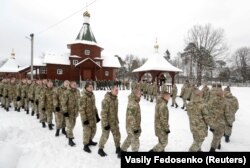 Servicemen of the Interior Ministry of Belarus stand in line to kiss a cross during a service to celebrate Orthodox Christmas at a military base in Minsk on January 7.