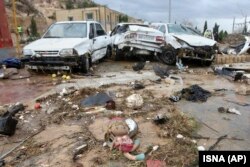 A child's doll lies in front of destroyed cars after flooding in the southern city of Shiraz.