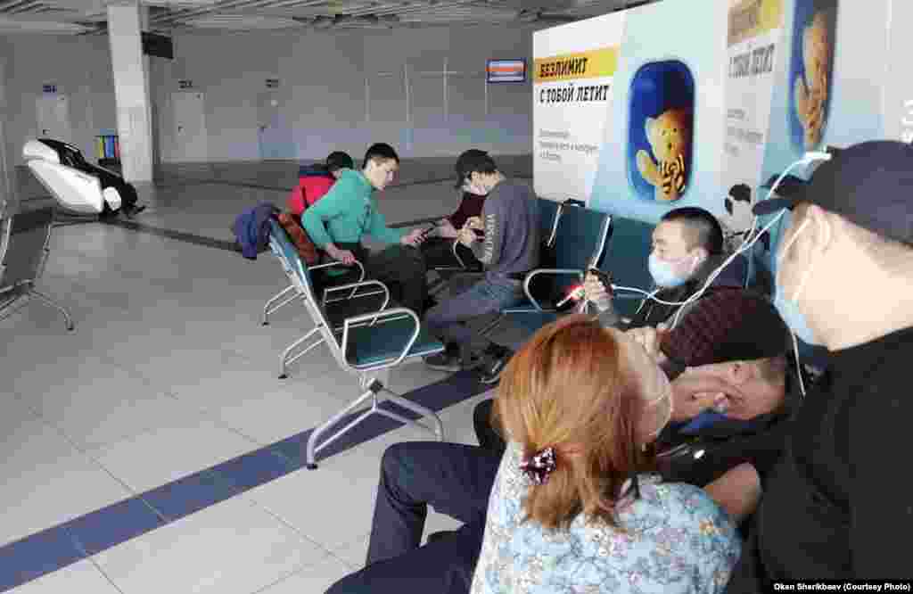 Kirghizi blocați pe aeroportul Tolmacevo, verificându-și telefoanele. E una din câteva fotografii făcute de Oken Șerikbaev, un cetățean kirghiz care așteaptă și el să se întoarcă acasă.