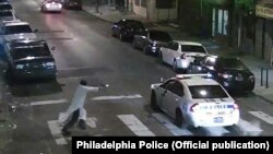Полиция көлігіне қарата оқ атып тұрған ер адам, Филадельфия, АҚШ. 7 қаңтар 2015 жыл.