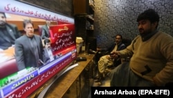 People watch a TV broadcast of Pakistani Prime Minister Imran Khan addressing the Parliament on February 28.