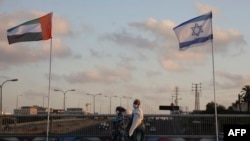 Women wearing face masks against the coronavirus walk past United Arab Emirates and Israeli flags at the Peace Bridge in Netanya, Israel, Sunday, Aug. 16, 2020. 