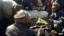 Afghan men and a woman gather around the bodies of civilians, including children, who were allegedly killed by Islamic State (IS) militants in Ghor province on October 26.